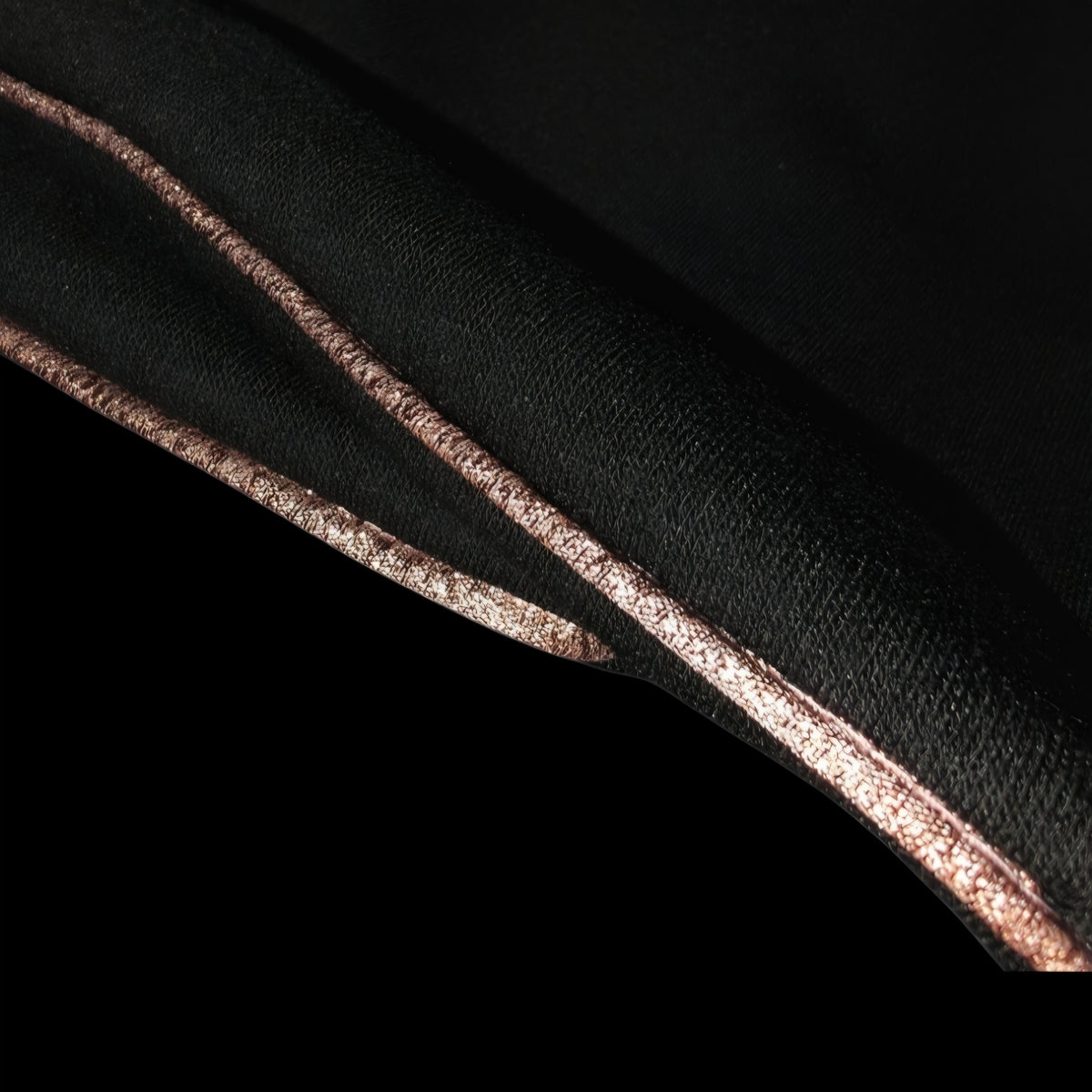 Close up of rose gold shimmer piping on black polar fleece stirrup socks/covers