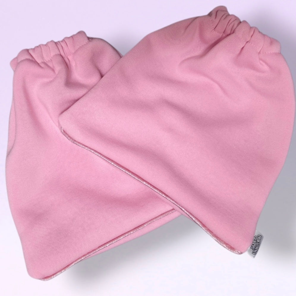 A pair of Fairy Floss Pink knit stirrup socks with elasticized cuffs, and Baby Pink shimmer piping, shown overlapping on a light lavender background.